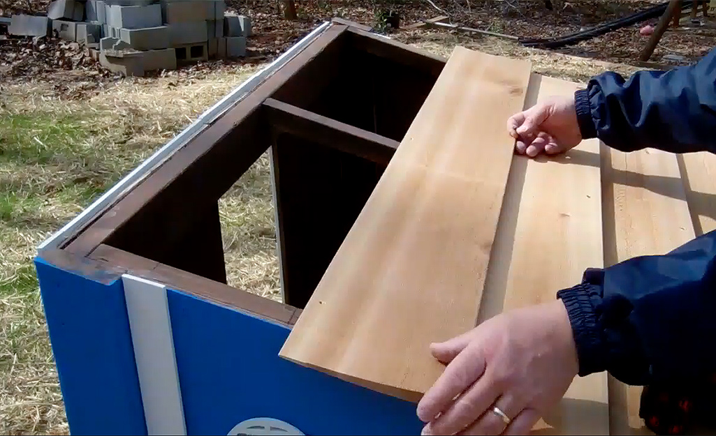 Someone adding a roof to a blue chicken coop. Someone adding a roof to a blue chicken coop.