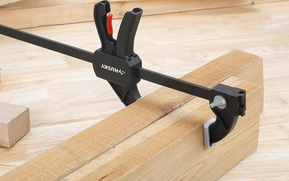 A clamp holding two pieces of wood together A clamp holding two pieces of wood together