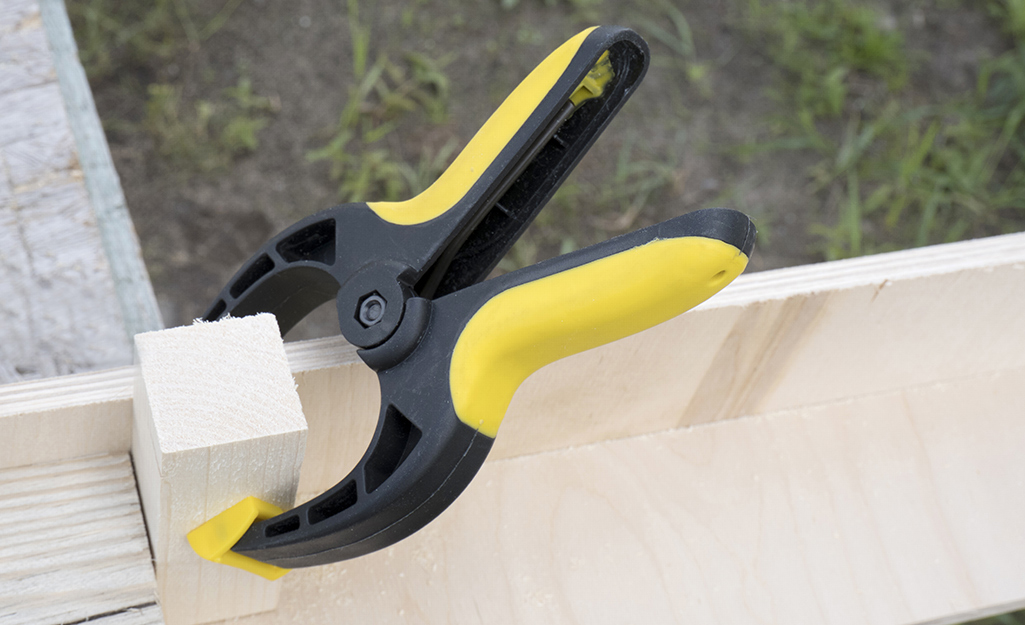 A clamp holding two pieces of wood together. A clamp holding two pieces of wood together.