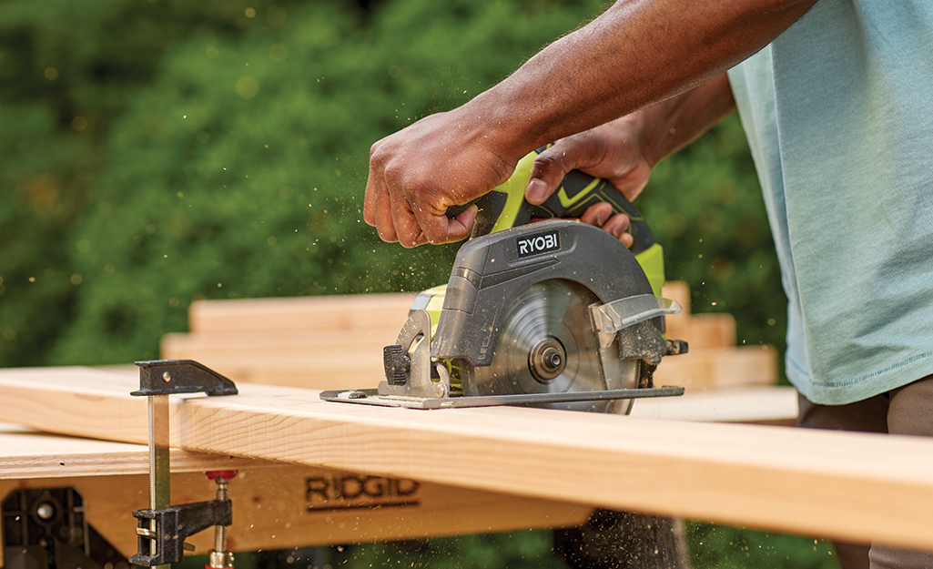 A person cuts a board with a circular saw.