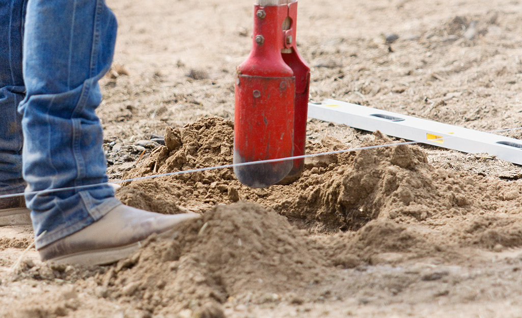 A hole being dug in the ground using a post hole digger. A hole being dug in the ground using a post hole digger.