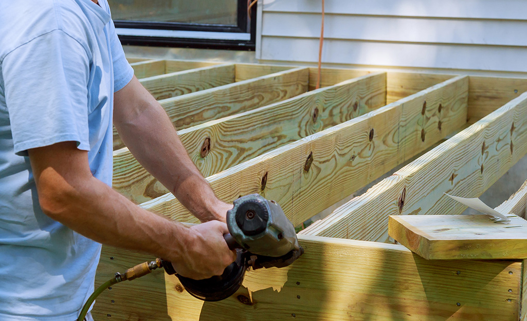 Man installs a deck beam using a power drill. Man installs a deck beam using a power drill.