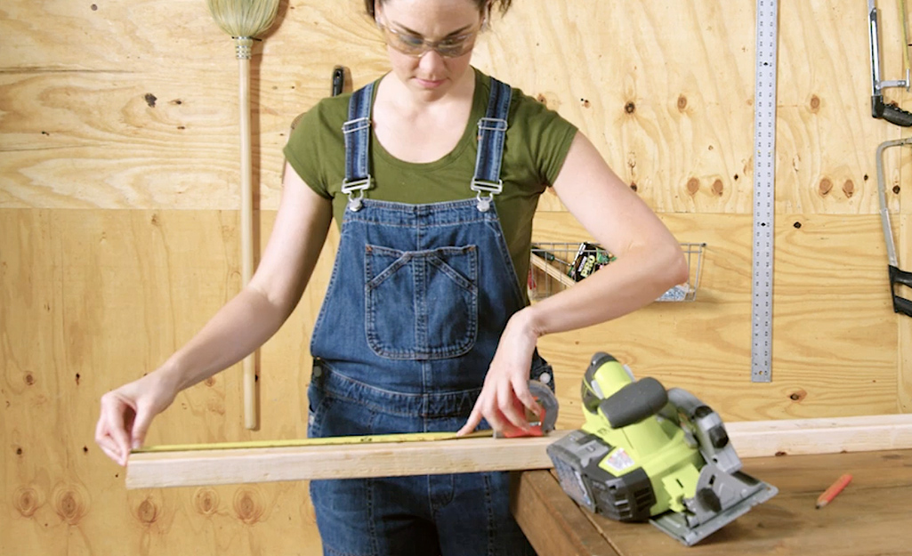 A worker measures studs for the dog house.