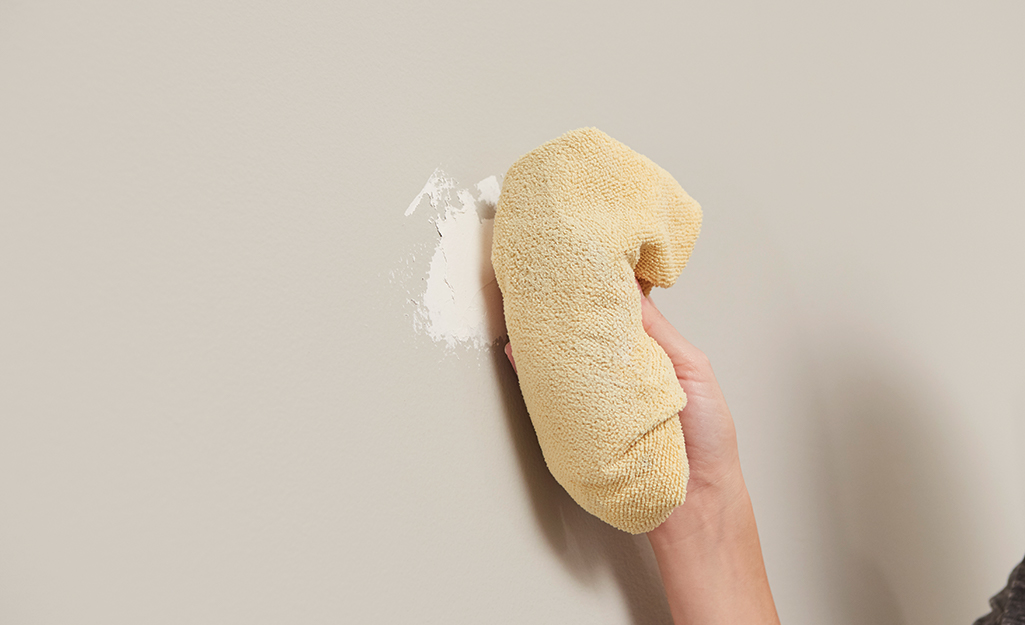 A rag is used to clean a wall. 