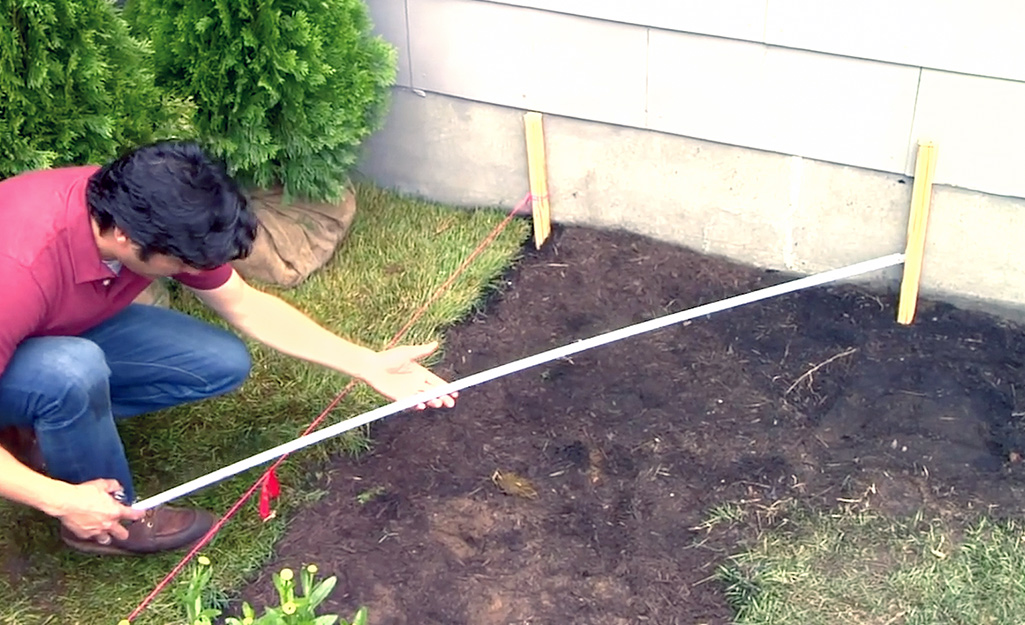 A person uses 3-4-5 method to measure for a fence installation.