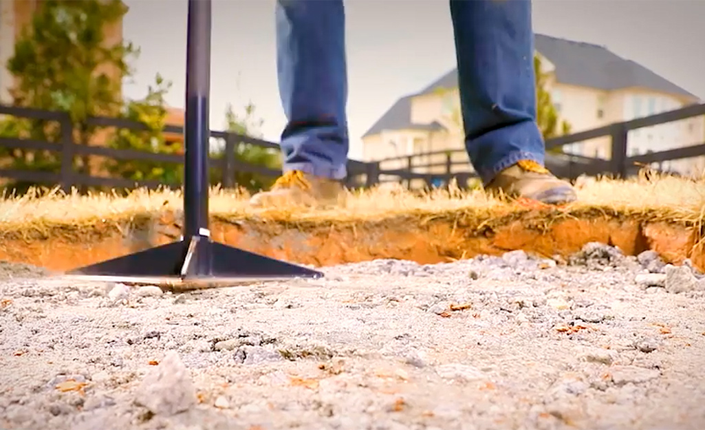 A person tamping the gravel base of a fire pit.