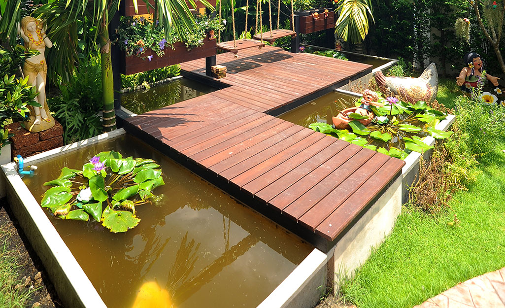 An above ground fish pond built under a wood walkway.