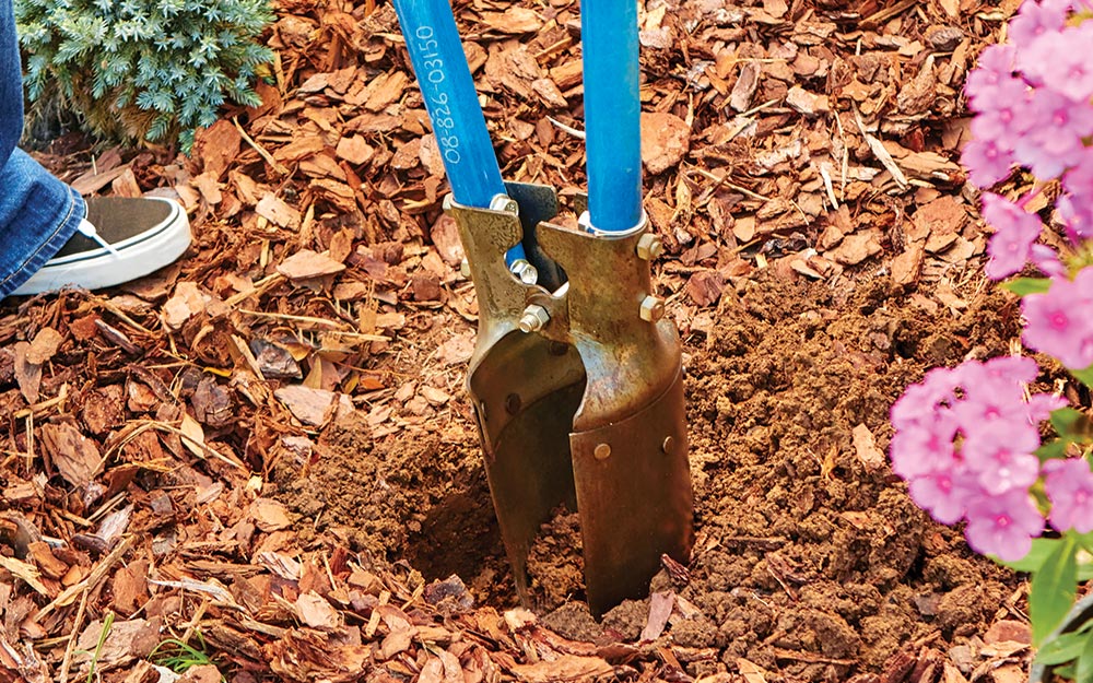 A post hold digger is used to make a hole for the posts of a garden arbor.