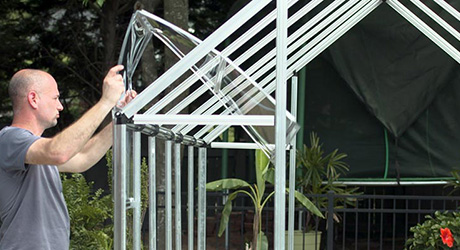 Person installing greenhouse wall panels. Person installing greenhouse wall panels.