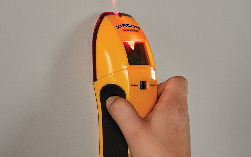 person using a stud finder on a blank wall person using a stud finder on a blank wall