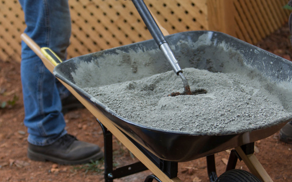 A person mixing concrete in a wheelbarrow.