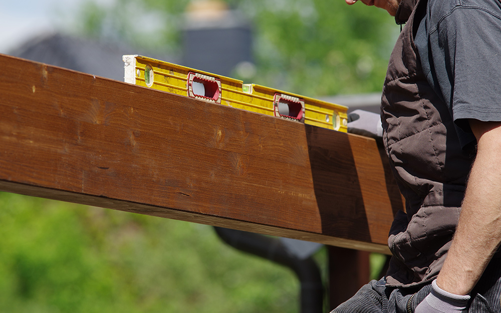 A man checking the level of a a crossbeam. A man checking the level of a a crossbeam.