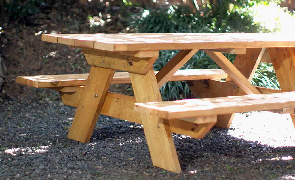 A beautifully stained DIY wood picnic table sitting in the shade.
