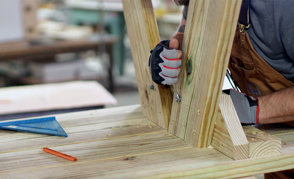 Picnic table legs being bolted to the bottom of a tabletop.