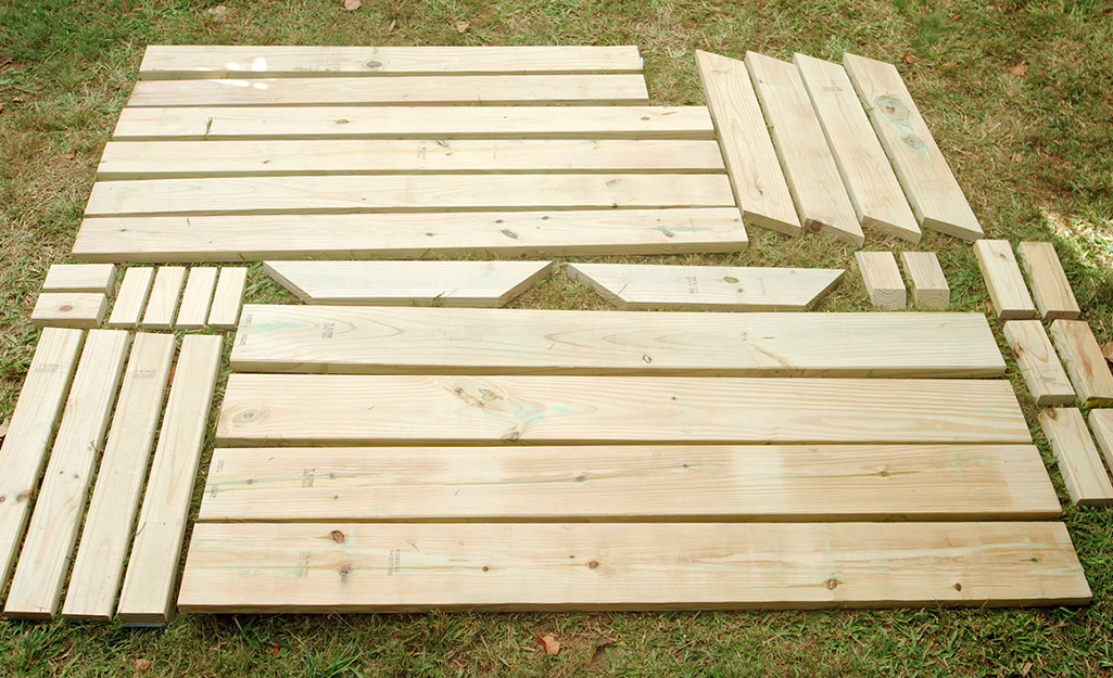 Wooden parts of a picnic table arranged on grass.