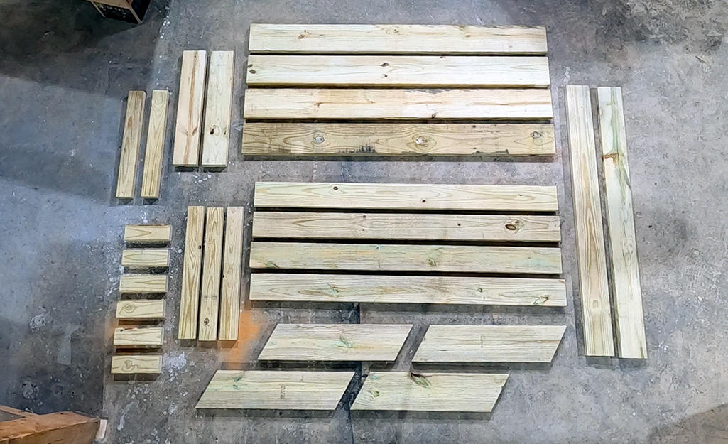 Pieces of cut wood for building a picnic table lay on the floor of a workshop.