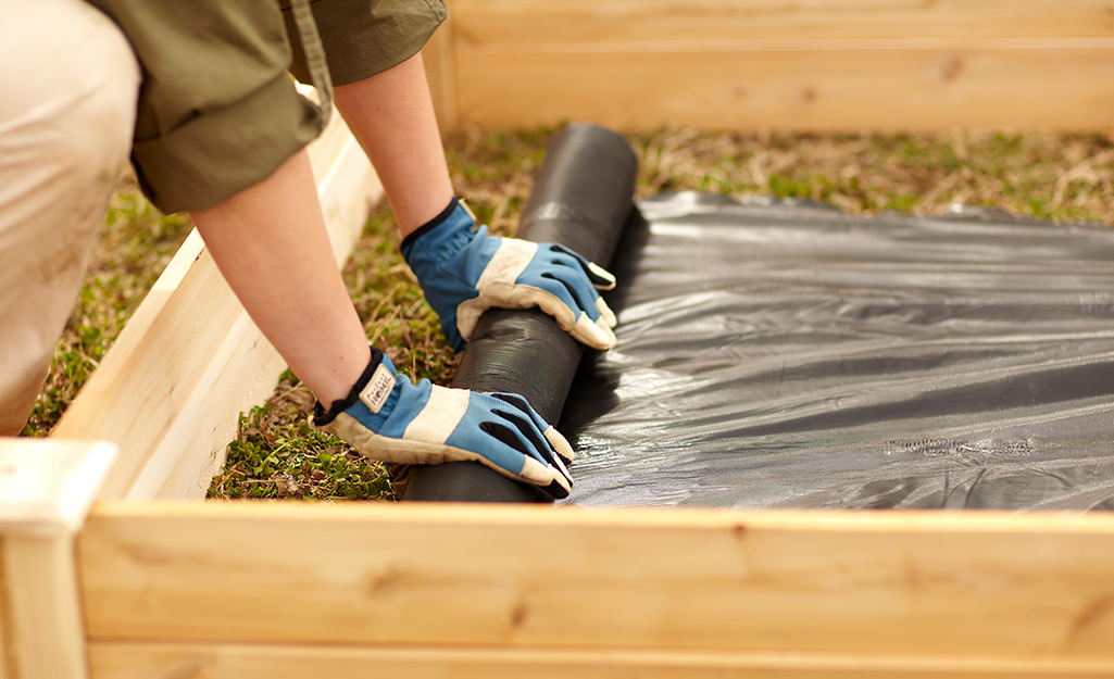 Garden soil being poured into a raised garden bed.