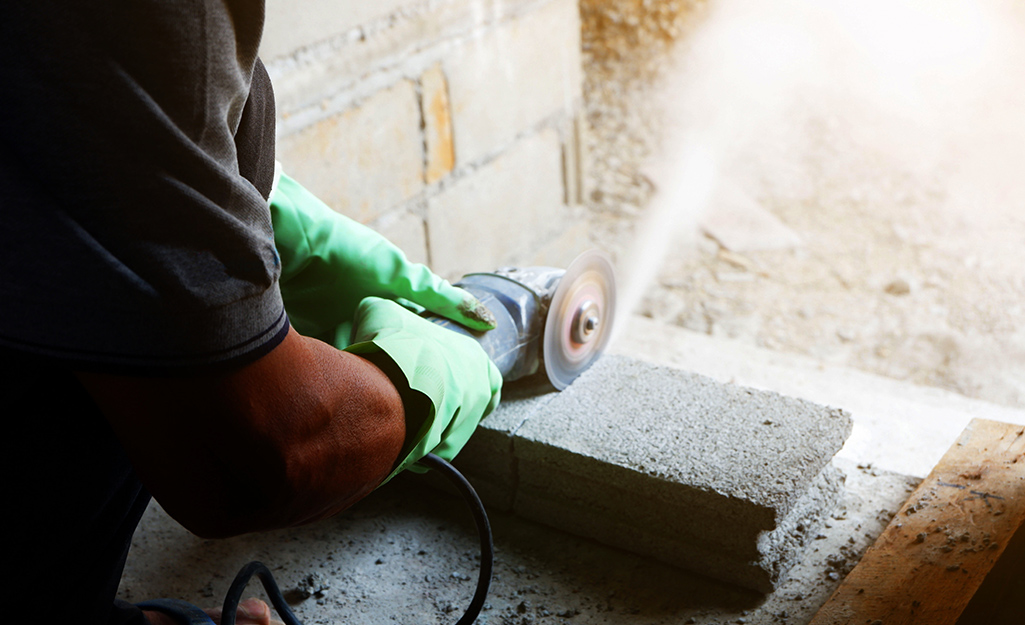 A person cutting a cement block with a masonry saw.