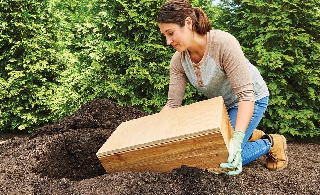 A person places a finished root cellar in a hole in the ground.