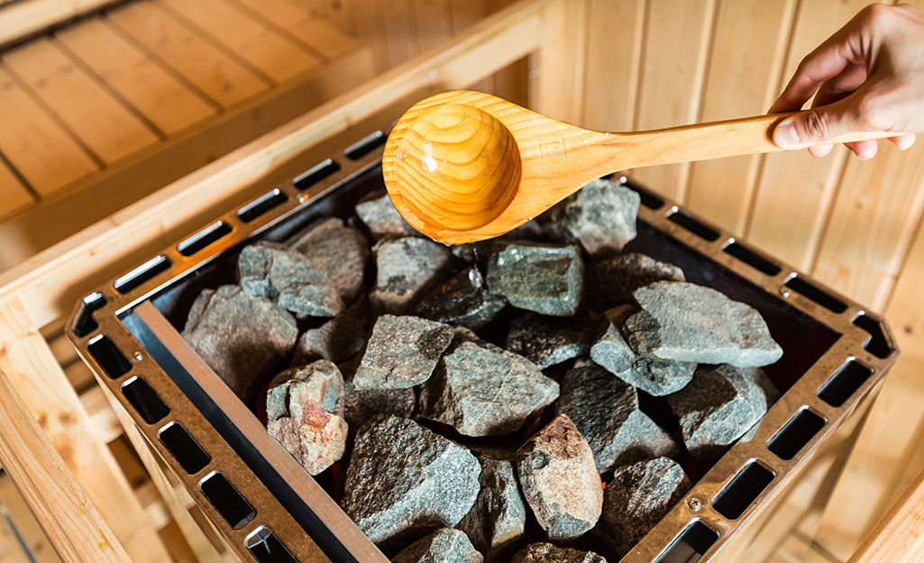 Someone pours water over rocks in a sauna.