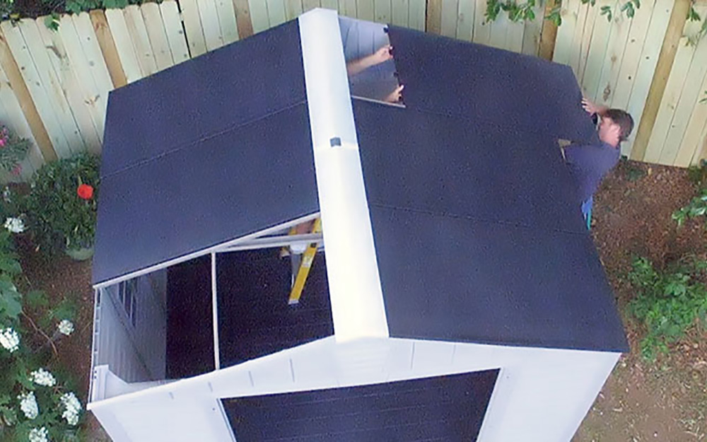 The last of the roof panels are added to a DIY shed. The last of the roof panels are added to a DIY shed.