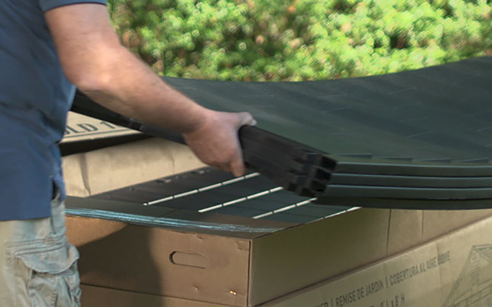 A man unpacks the pieces of a DIY shed. A man unpacks the pieces of a DIY shed.
