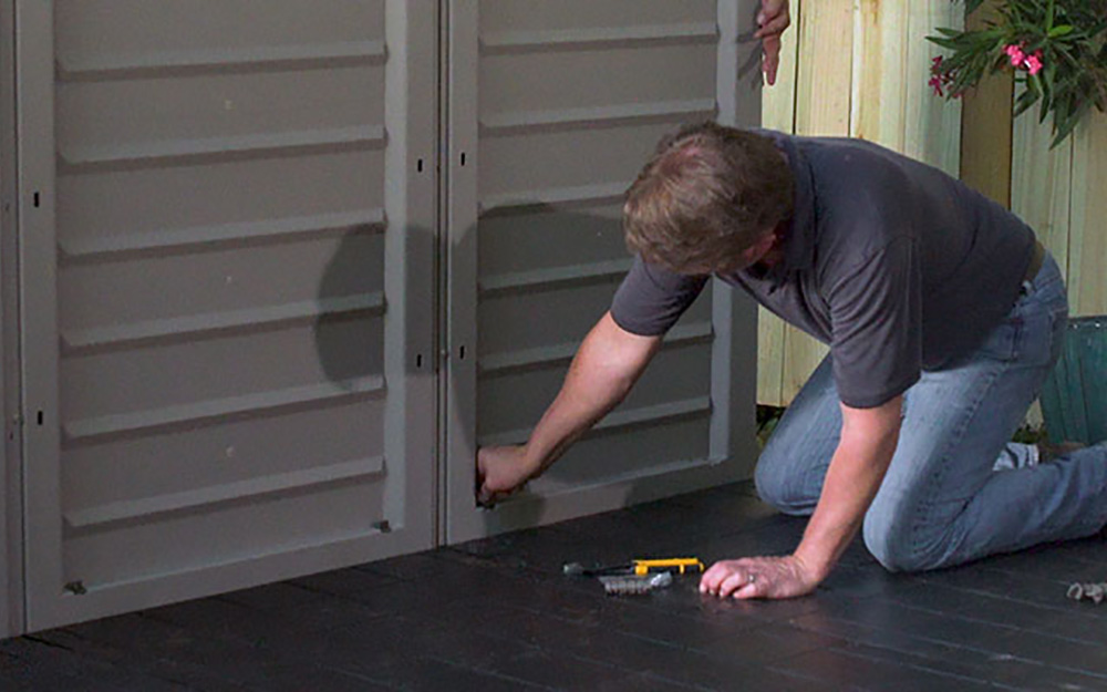 A man assembles a wall in a DIY shed. A man assembles a wall in a DIY shed.