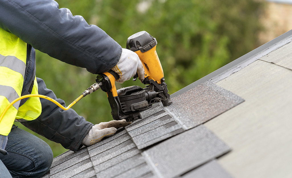 A man installing roof roofing shingles.