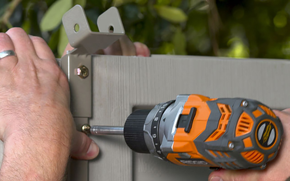 A man screws in the shelf support for a DIY shed. A man screws in the shelf support for a DIY shed.