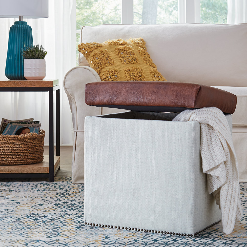 An upholstered storage ottoman in front of a sofa.