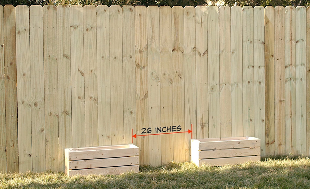 Two wood planter boxes placed 26 inches apart in front of a fence.
