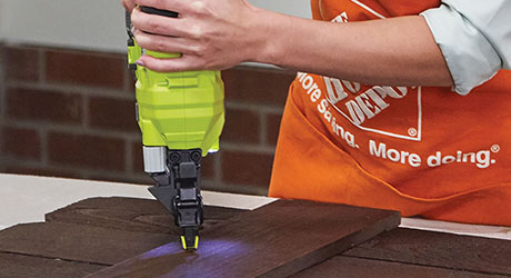 Person using a brad nailer to assemble all pieces of project Person using a brad nailer to assemble all pieces of project