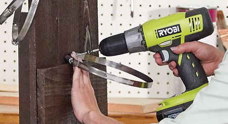 Person drilling metal rings into a board Person drilling metal rings into a board