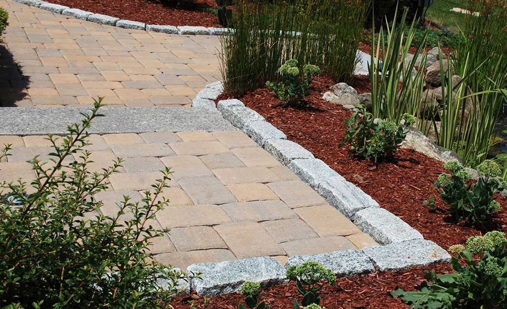 A walkway edged with pavers beside a garden bed.