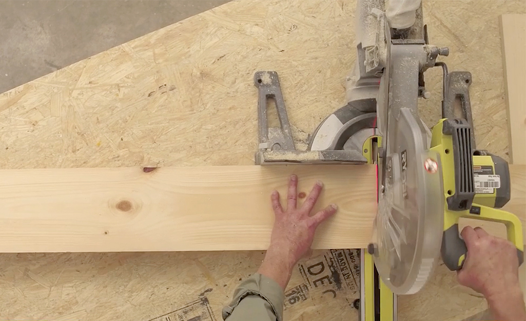 A man uses a circular saw to cut the lumber to build a wooden bed frame A man uses a circular saw to cut the lumber to build a wooden bed frame