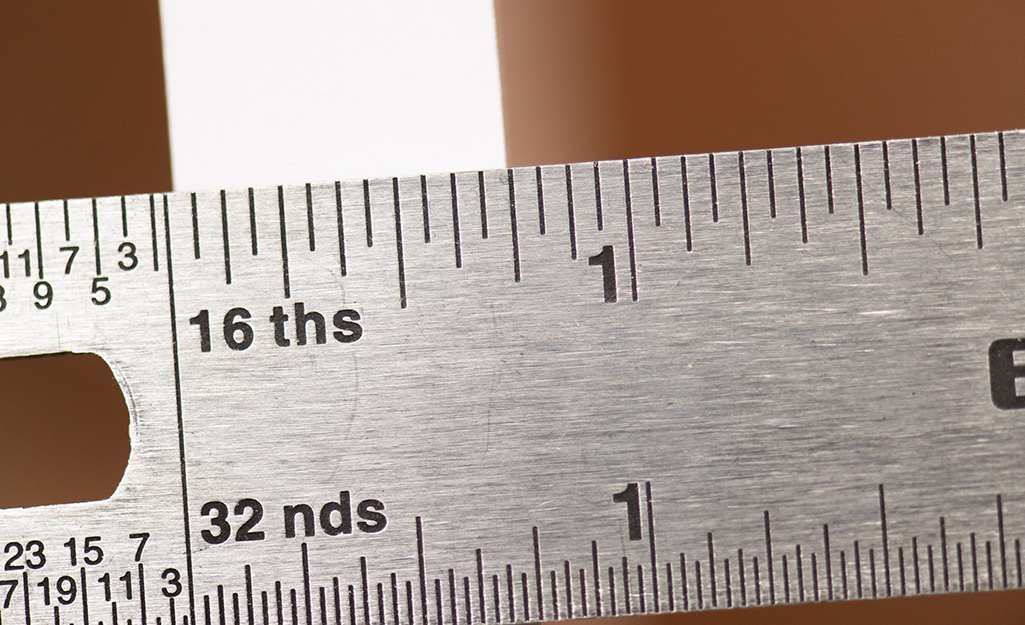 A ruler on the edge of a board, showing that 1 by or 1x lumber is actually 3/4 of an inch thick.