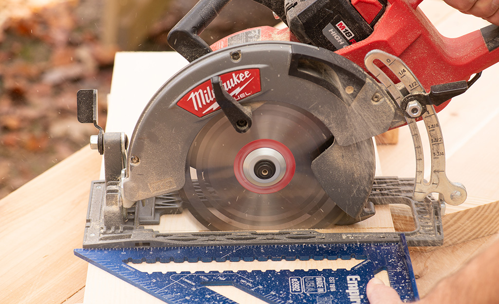 A person using a saw to cut boards.