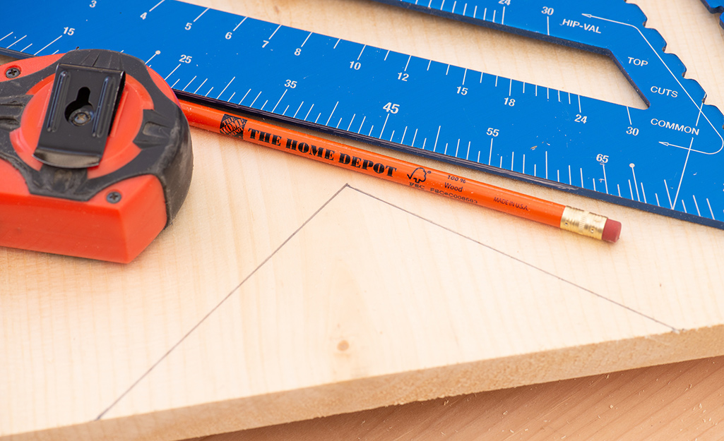 A ruler, tape measure and pencil on a marked board.