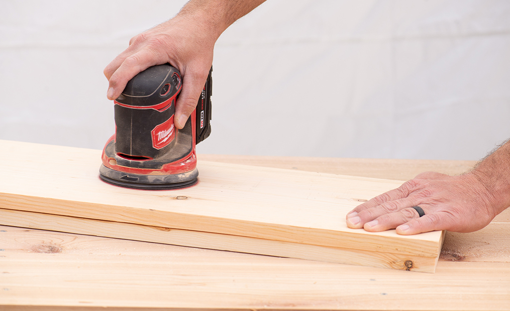 A person sanding wooden boards.