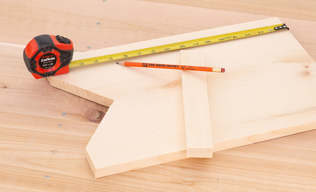 A tape measure and pencil on cut wooden boards.