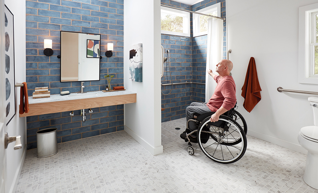 A man in a wheelchair looks at the shower in his new accessible bathroom.