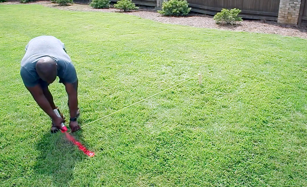 A person marking off an area of lawn with spray paint.