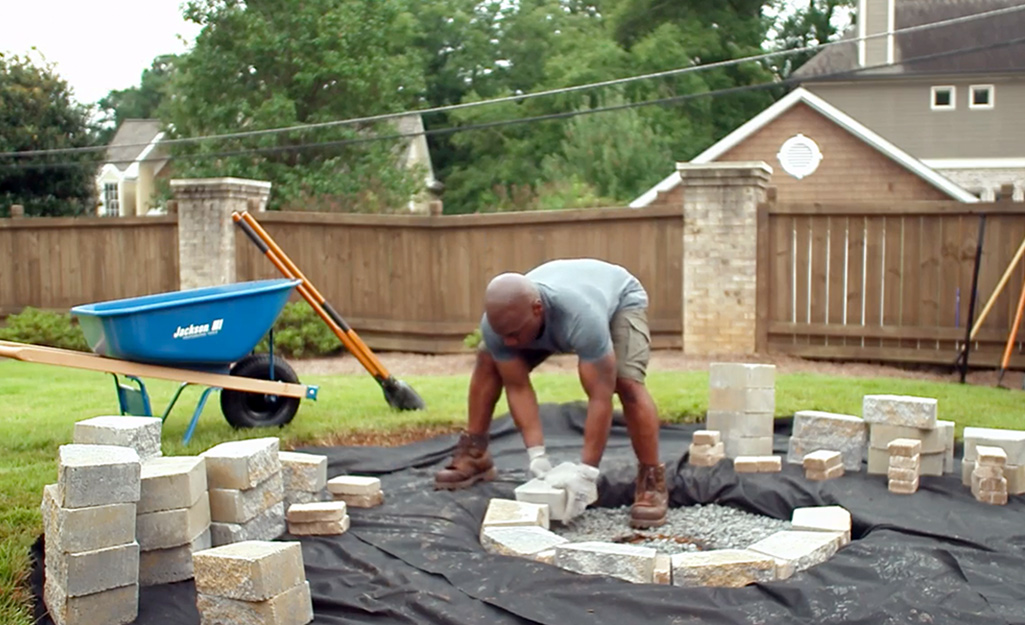 A person stacking pavers over landscape liner.