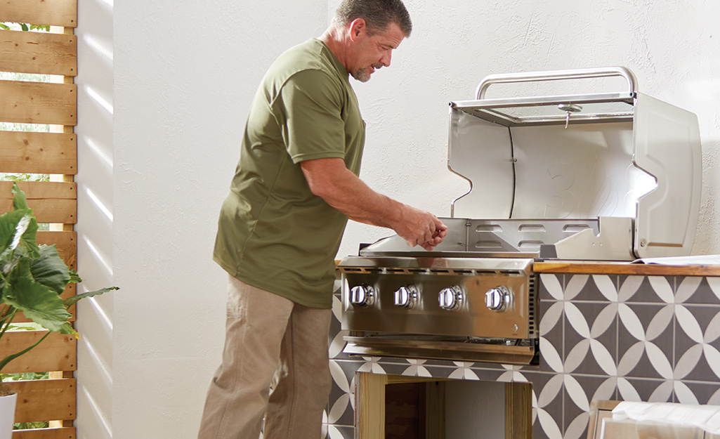 A man installs a grill in a DIY outdoor kitchen counter.