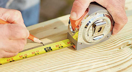 A person measuring and marking wood. A person measuring and marking wood.