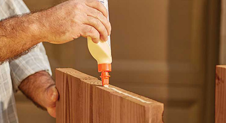 A person spreading wood glue on the edge of a board. A person spreading wood glue on the edge of a board.