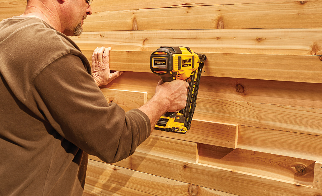 A person attaching wooden boards with a nail gun