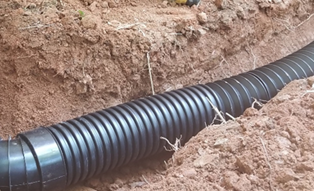 A corrugated pipe drain in a shallow trench.
