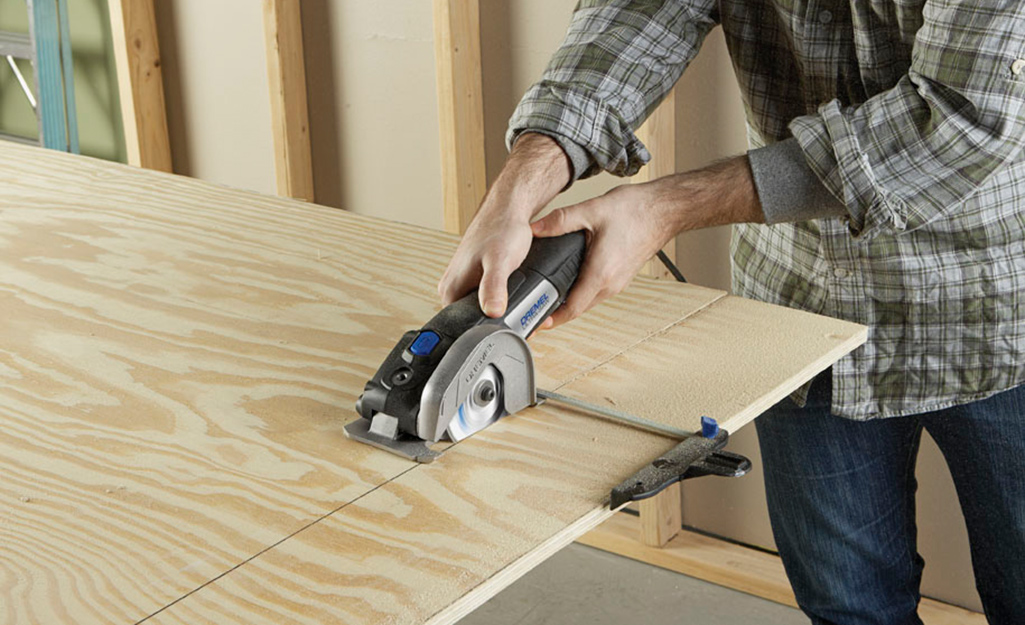 A person cutting plywood for utility shelves. A person cutting plywood for utility shelves.