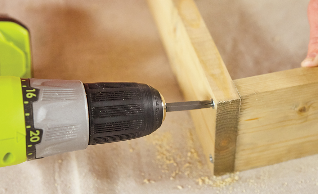 A power drill driving screws to adjoin two pieces of plywood for utility shelves. A power drill driving screws to adjoin two pieces of plywood for utility shelves.